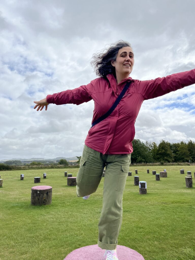 A woman in a purple raincoat standing on a small pillar in the wind