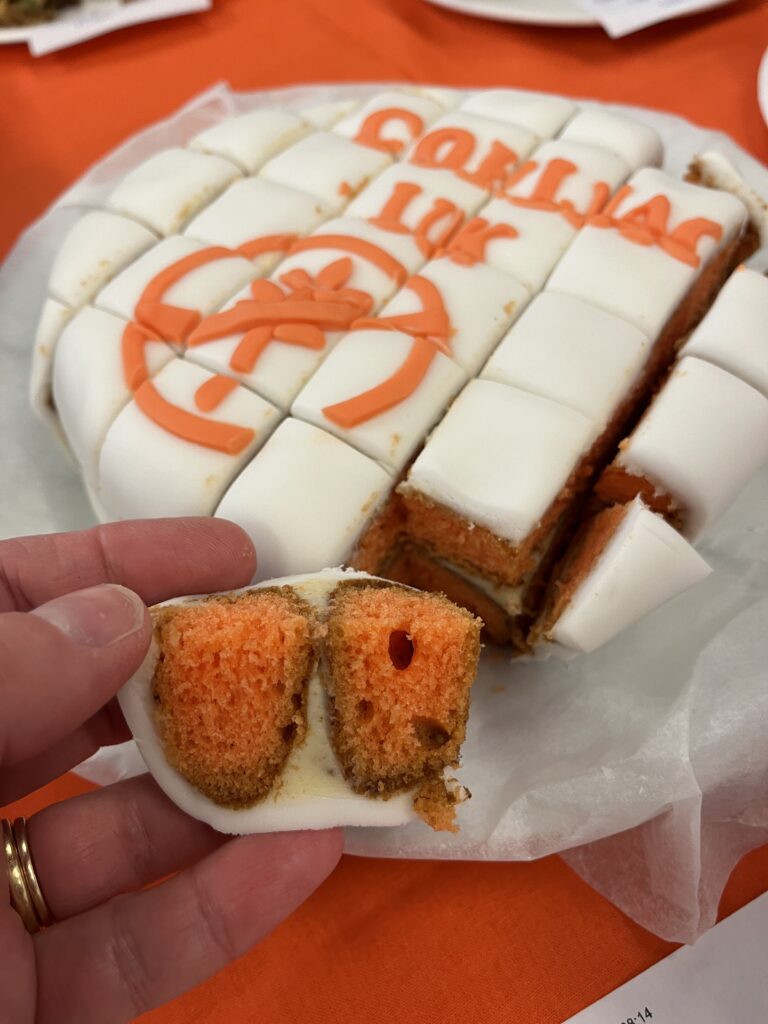 A hand holding a piece of orange cake